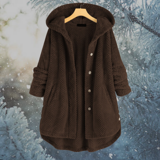 Brauner Damenmantel mit Kapuze, Knöpfen und Taschen, Wintermode, vor verschneitem Hintergrund.