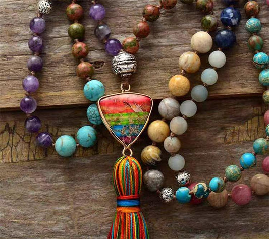 Bunte handgemachte Boho-Halskette mit Edelsteinen und Quaste auf Holzoberfläche.