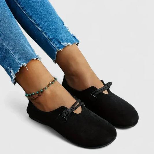 Svarta mockaloafers med knutna snören, sedda från sidan på en modell med uppvikta jeans 2