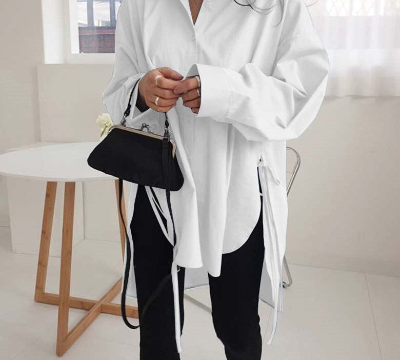 Frau in weißer Oversize-Bluse, schwarze Tasche, moderne Mode, minimalistisch, stilvoll.