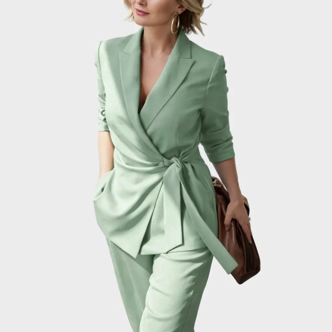 Närbild på ljusgrön blazer med omlott och skärp knutet i midjan, burna av en leende modell med brun väska. 6