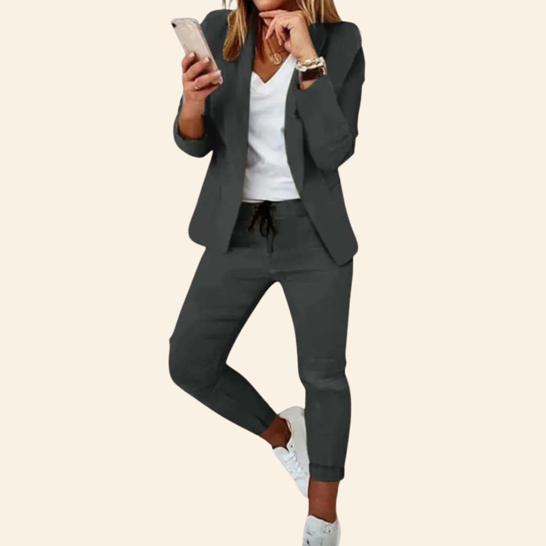 Frau in grauem Jogginganzug mit Blazer, Smartphone in der Hand, modisch, lässig, Business-Look.