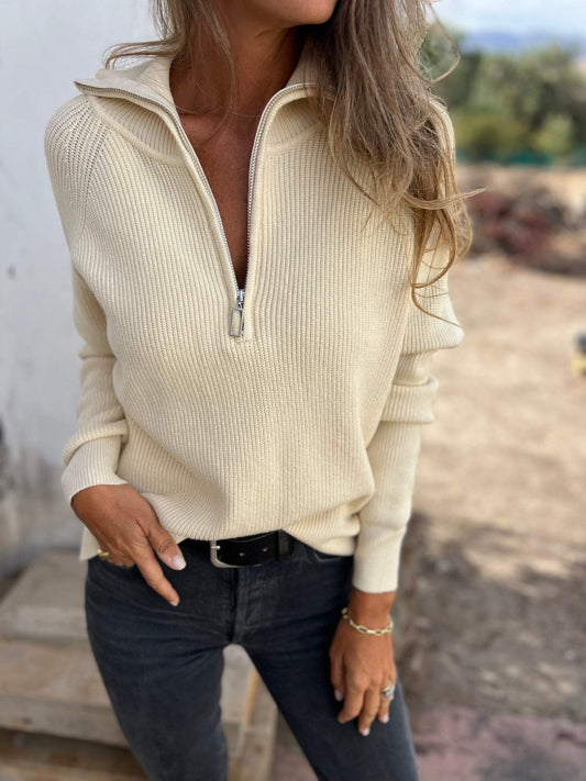 Frau in cremefarbenem Strickpullover mit Reißverschluss, schwarze Jeans, lässiger Herbstlook.