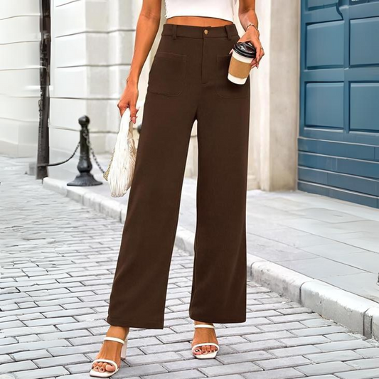 Frau in brauner Hose, weißem Top, hält Kaffeebecher und Tasche, modisch, städtische Straße.