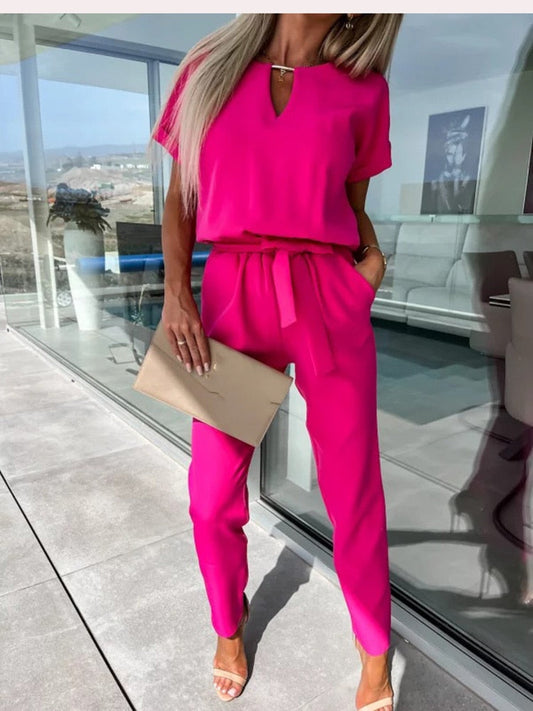 Frau in pinkem Sommeranzug mit Clutch, moderne Mode, elegantes Outfit, helle Farben.