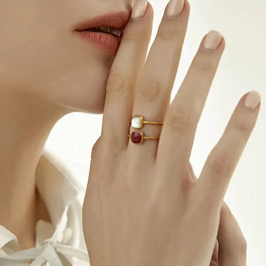 Frau trägt goldene Ringe mit quadratischen Steinen, eleganter Schmuck, Nahaufnahme.