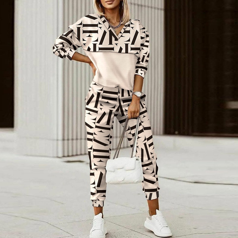 Frau in geometrischem Print-Sweatshirt und Jogginghose, weiße Sneaker, weiße Handtasche.