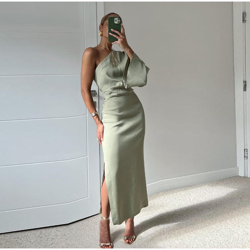Frau in grünem, schulterfreiem Kleid mit Schlitz, elegantes Abendoutfit, modisch, modern.