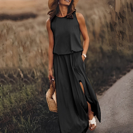 Frau in elegantem, schwarzem Maxikleid mit Strohhut und Korbtasche auf ländlichem Weg.