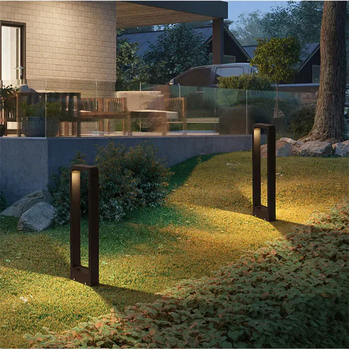 Moderne schwarze Gartenleuchten beleuchten Rasen vor Haus, LED-Außenbeleuchtung.