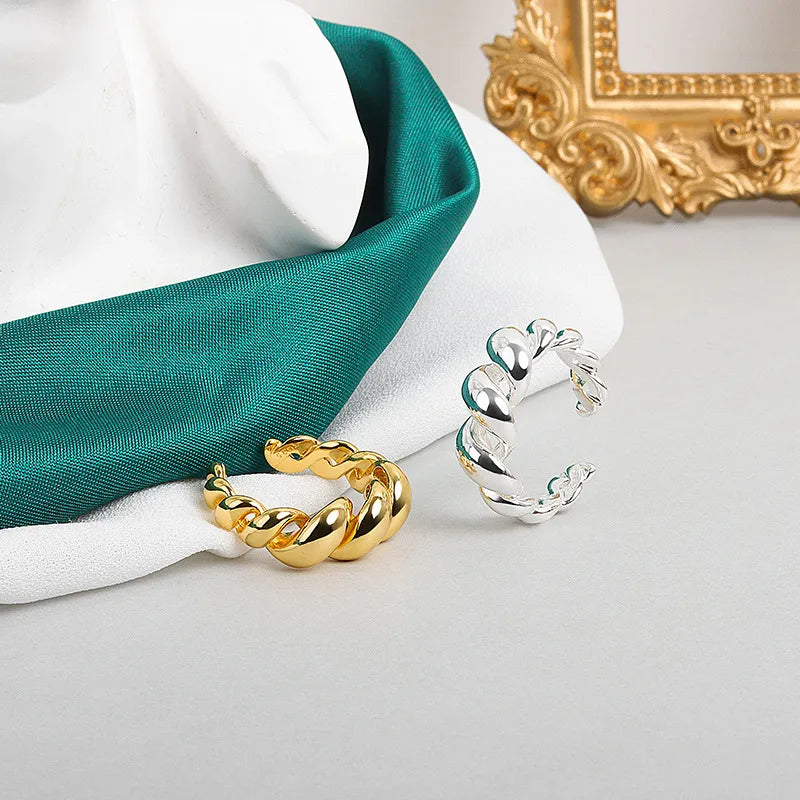 Goldene und silberne gedrehte Creolen auf grauem Hintergrund, Schmuck, modisch, elegant.