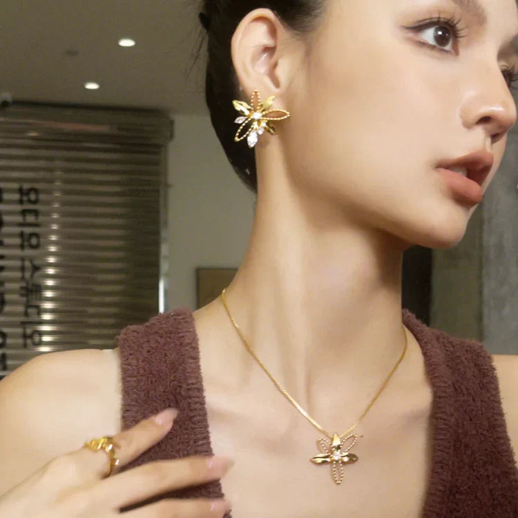 Frau mit goldener Libellen-Halskette und Ohrringen, eleganter Schmuck, Nahaufnahme.