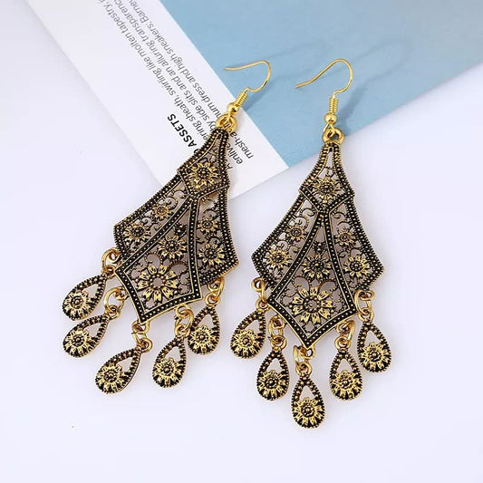 Goldene, orientalische Ohrringe mit filigranem Muster und Tropfenanhängern auf weißem Hintergrund.