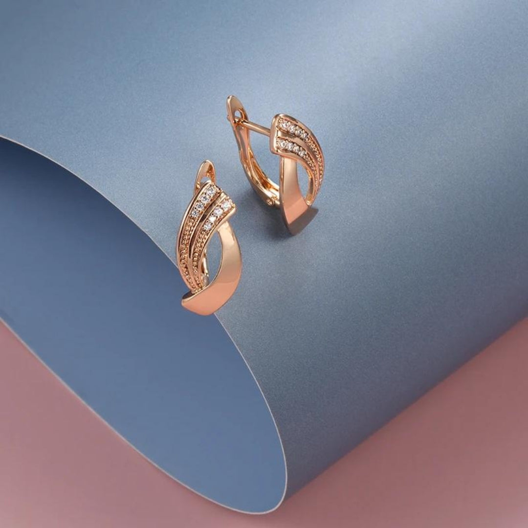 Goldene Ohrringe mit Diamanten auf blauem Hintergrund, elegantes Schmuckdesign.