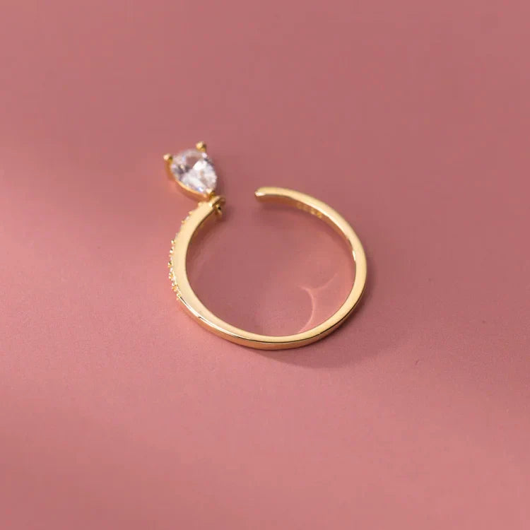 Goldener offener Ring mit Tropfen-Zirkonia, eleganter Schmuck, minimalistisches Design.