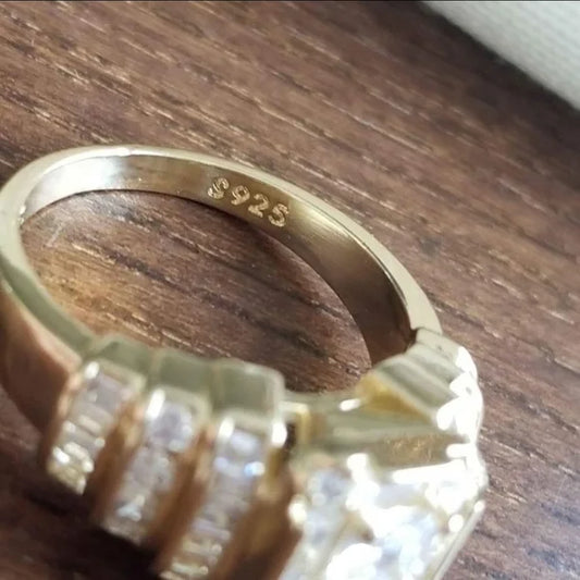 Goldener Ring mit Zirkonia-Steinen, 925er Silberstempel, auf Holzoberfläche.