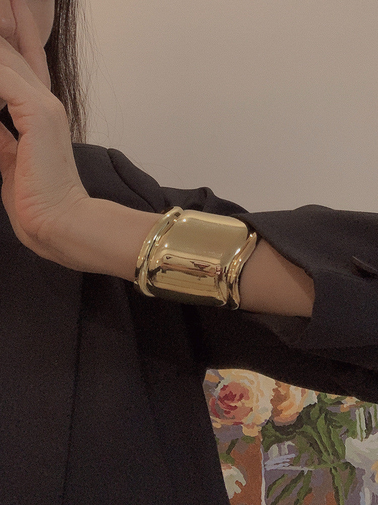 Goldenes, breites Metallarmband mit asymmetrischen Öffnungen, modisches Accessoire.