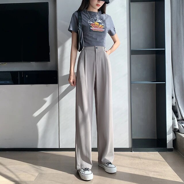 Frau in grauem T-Shirt und grauer Hose, modisch, lässig, urbaner Stil, Tageslicht.