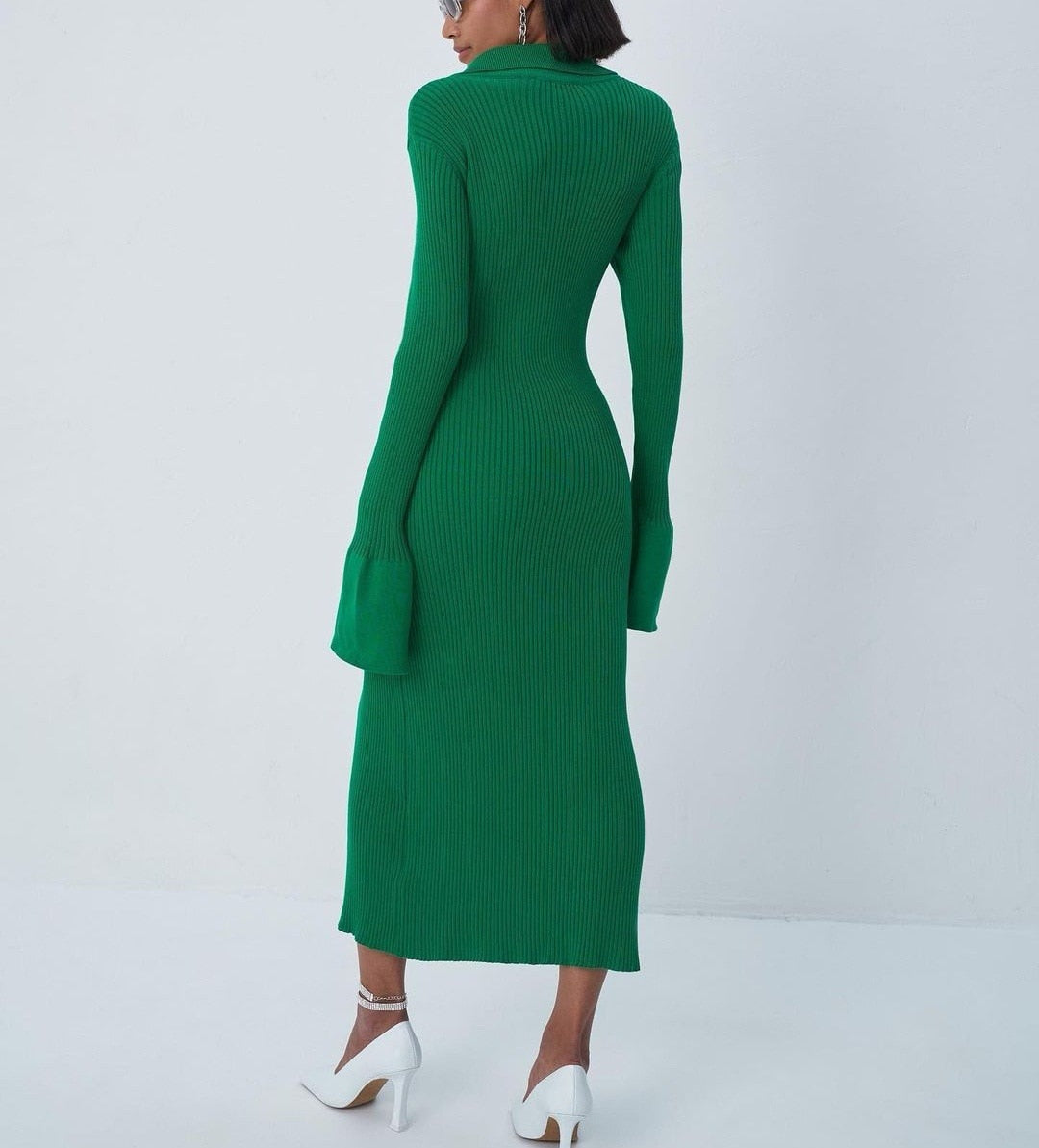 Frau in grünem, langem Strickkleid mit langen Ärmeln, elegantes Design, weiße High Heels.