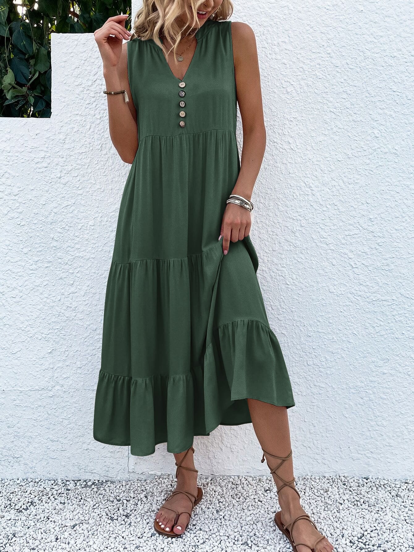 Frau in grünem Sommerkleid mit Knopfleiste, Sandalen, vor weißer Wand.