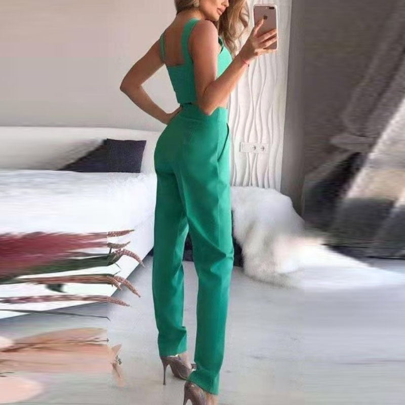 Frau in grünem Jumpsuit, elegantes Design, hohe Absätze, modernes Schlafzimmer, Modefotografie.