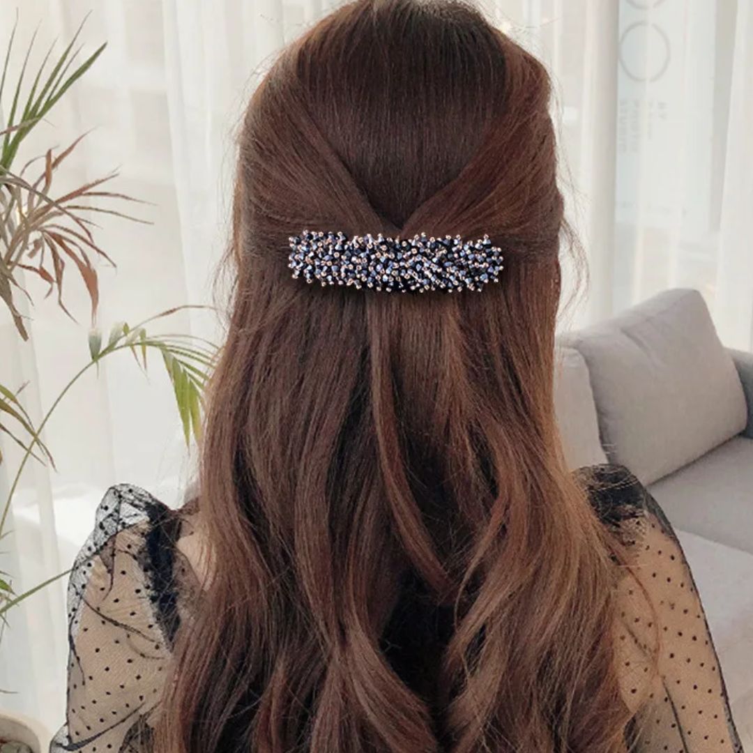Frau mit braunem Haar, Haarspange mit blauen Perlen, elegantes Accessoire, Rückansicht.
