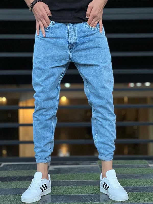 Mann trägt hellblaue Jeans und weiße Sneakers mit schwarzen Streifen, lässiger Streetwear-Look.