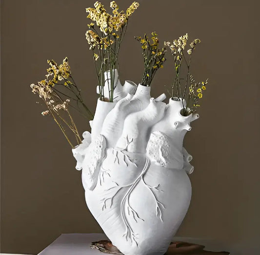 Weiße Herzvase aus Keramik mit getrockneten gelben Blumen, dekorative Wohnaccessoires.