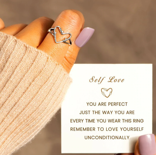 Hand mit silbernem Herzring und Karte, Selbstliebe, Geschenk, Schmuck, Damenmode, Nahaufnahme.