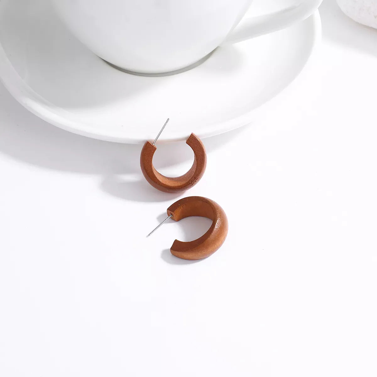 Braune Holz-Ohrringe auf weißem Hintergrund, minimalistisches Design, Modeschmuck.