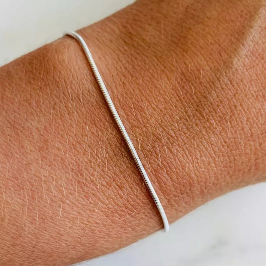Silbernes Schlangenarmband auf Handgelenk, minimalistisches Design, eleganter Schmuck.