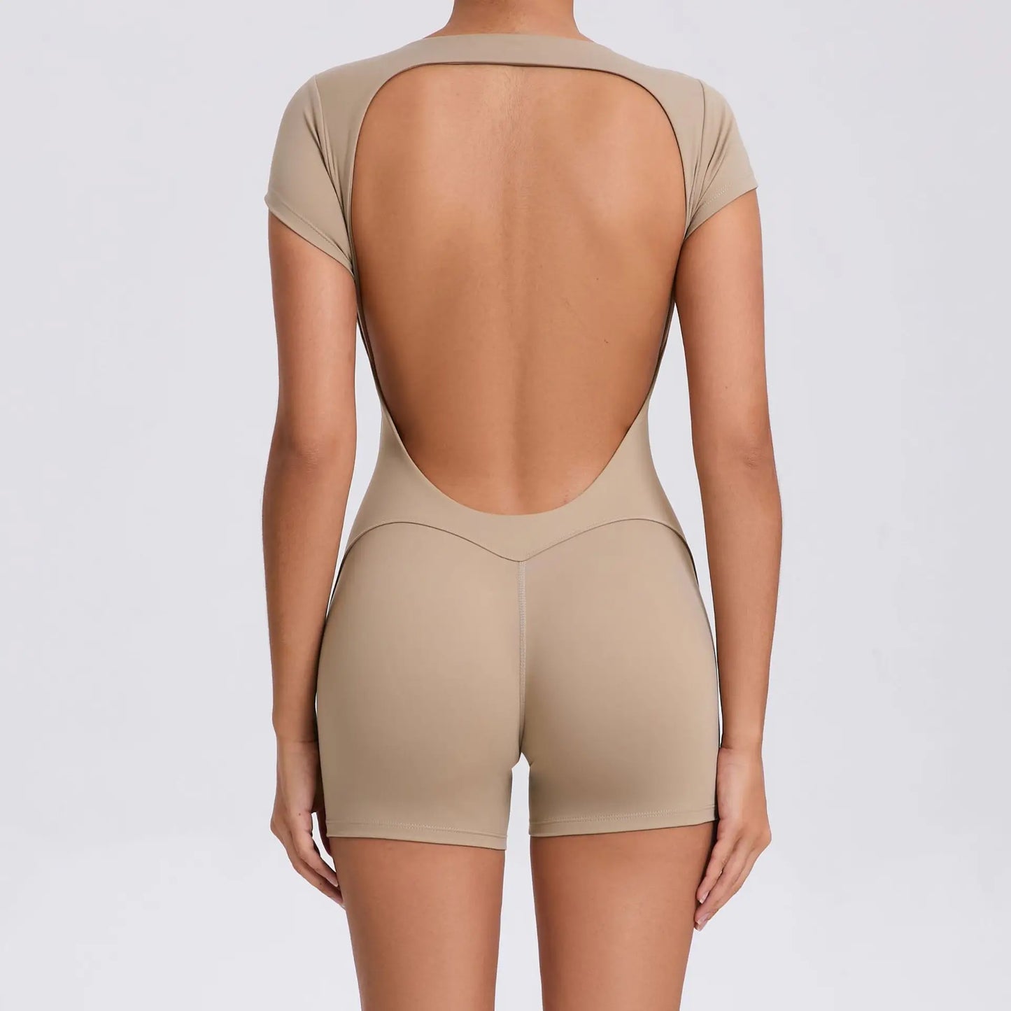 Beiger, rückenfreier Kurzoverall für Damen, eng anliegend, aus elastischem Material.