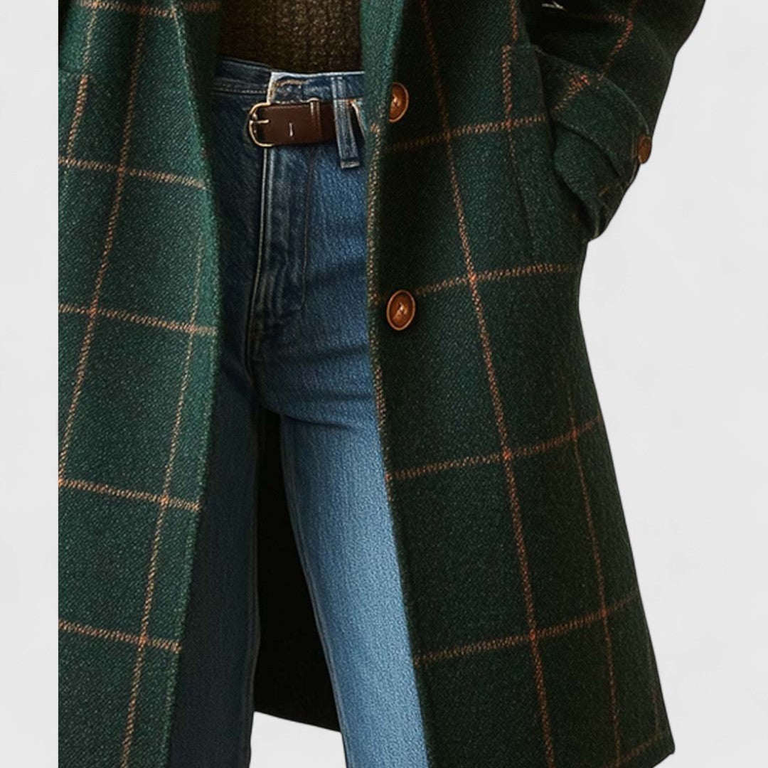 Närbild på kappans nedre framsida med knappar och ficka med klaff, där modellen har handen i fickan. 5