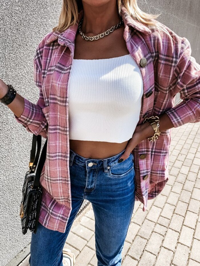 Frau in rosa kariertem Hemd, weißem Top, blauer Jeans; modische Herbstkleidung.
