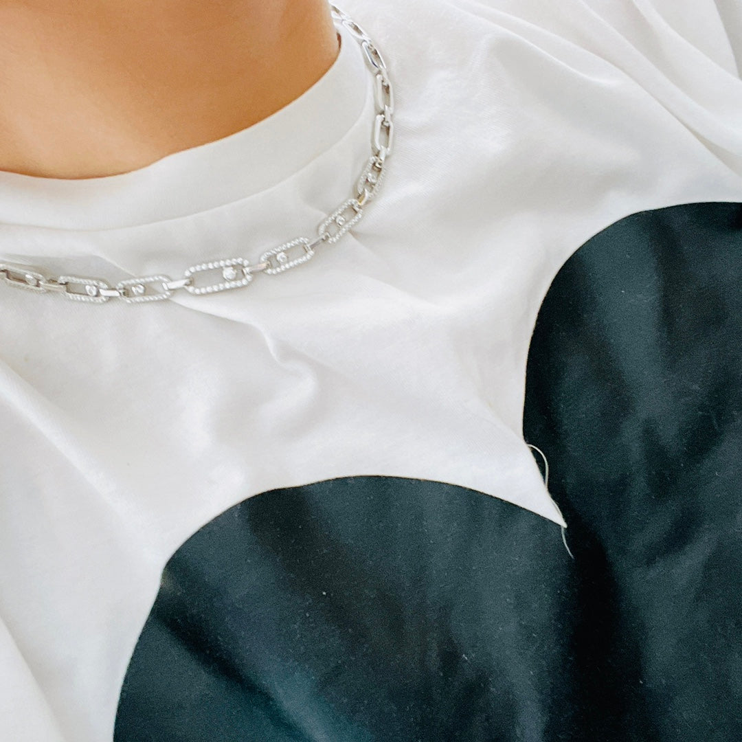 Silberne Halskette mit Kettengliedern auf weißem T-Shirt, luxuriöses Schmuckdesign.