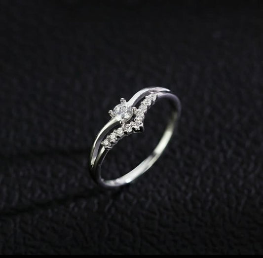 Silberner Diamantring mit geschwungenem Design auf schwarzem Hintergrund, eleganter Schmuck.