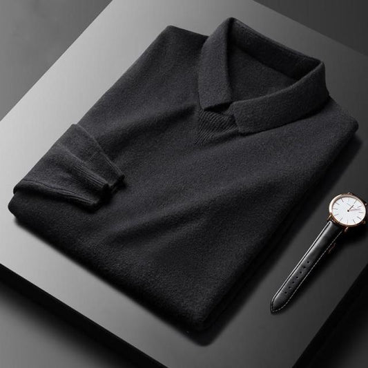 Schwarzer Herrenpullover aus Kaschmir, gefaltet, neben einer eleganten Armbanduhr auf schwarzem Tisch.
