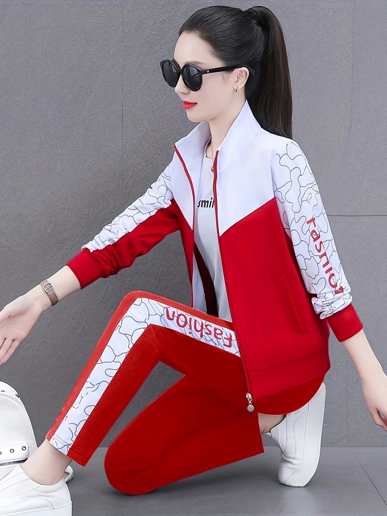 Frau in rotem Trainingsanzug mit weißen Details, Sonnenbrille, sportlich, modern, Freizeitmode.