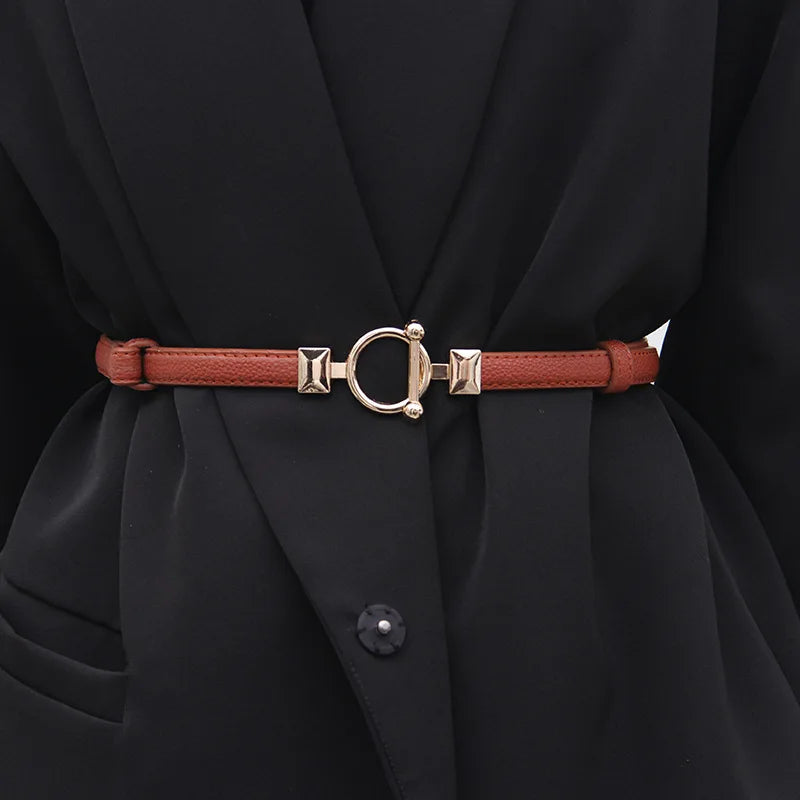 Brauner Ledergürtel mit goldener Schnalle, Damenmode, elegantes Accessoire, schwarzer Mantel.