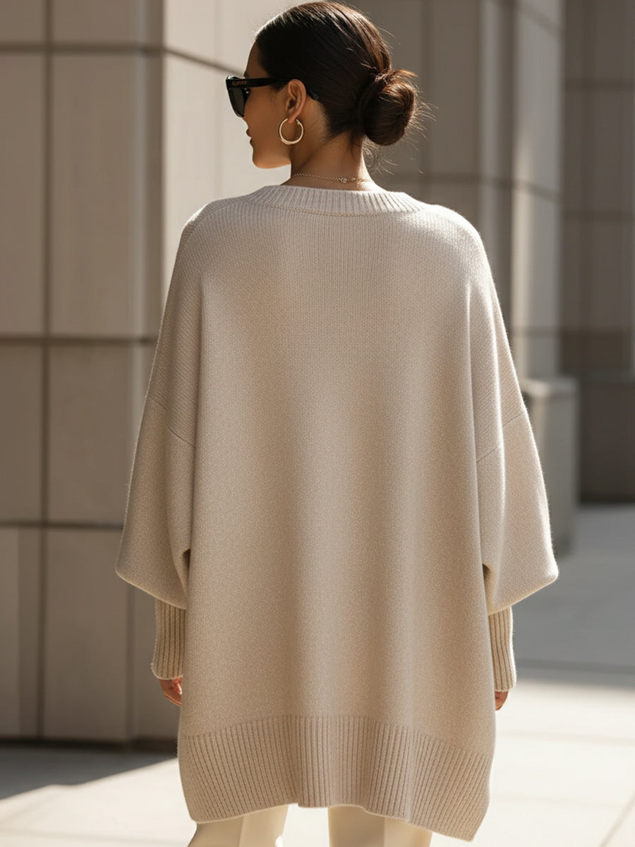 Modell fotad bakifrån i beige poncho med ribbad nederkant och uppsatt hår 5