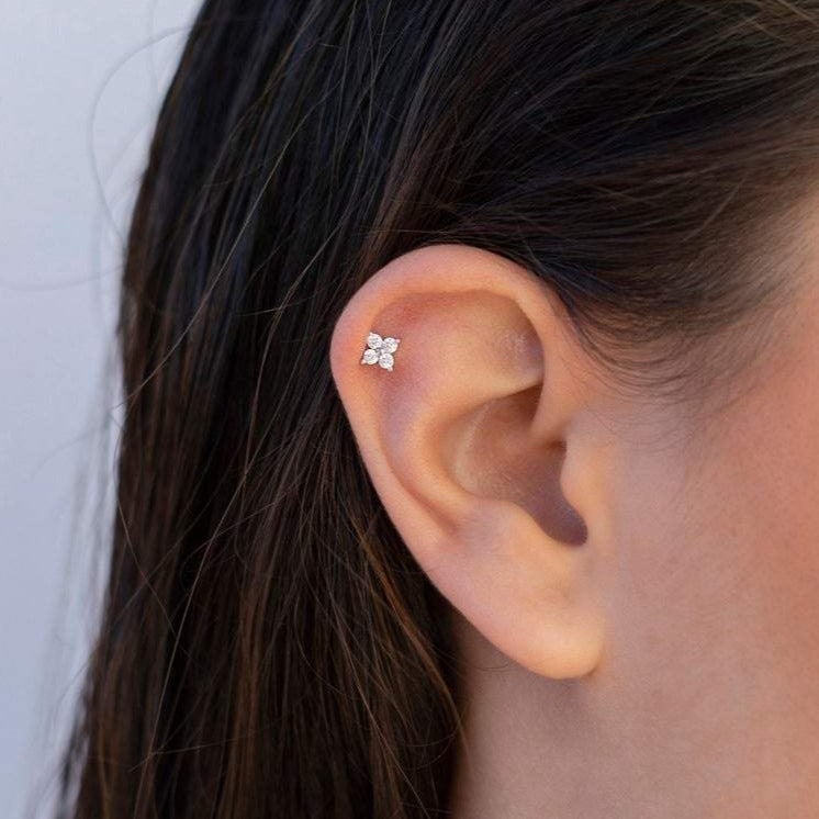 Ohrring am Ohr, silberner Stecker mit vier Diamanten, eleganter Schmuck, Nahaufnahme.