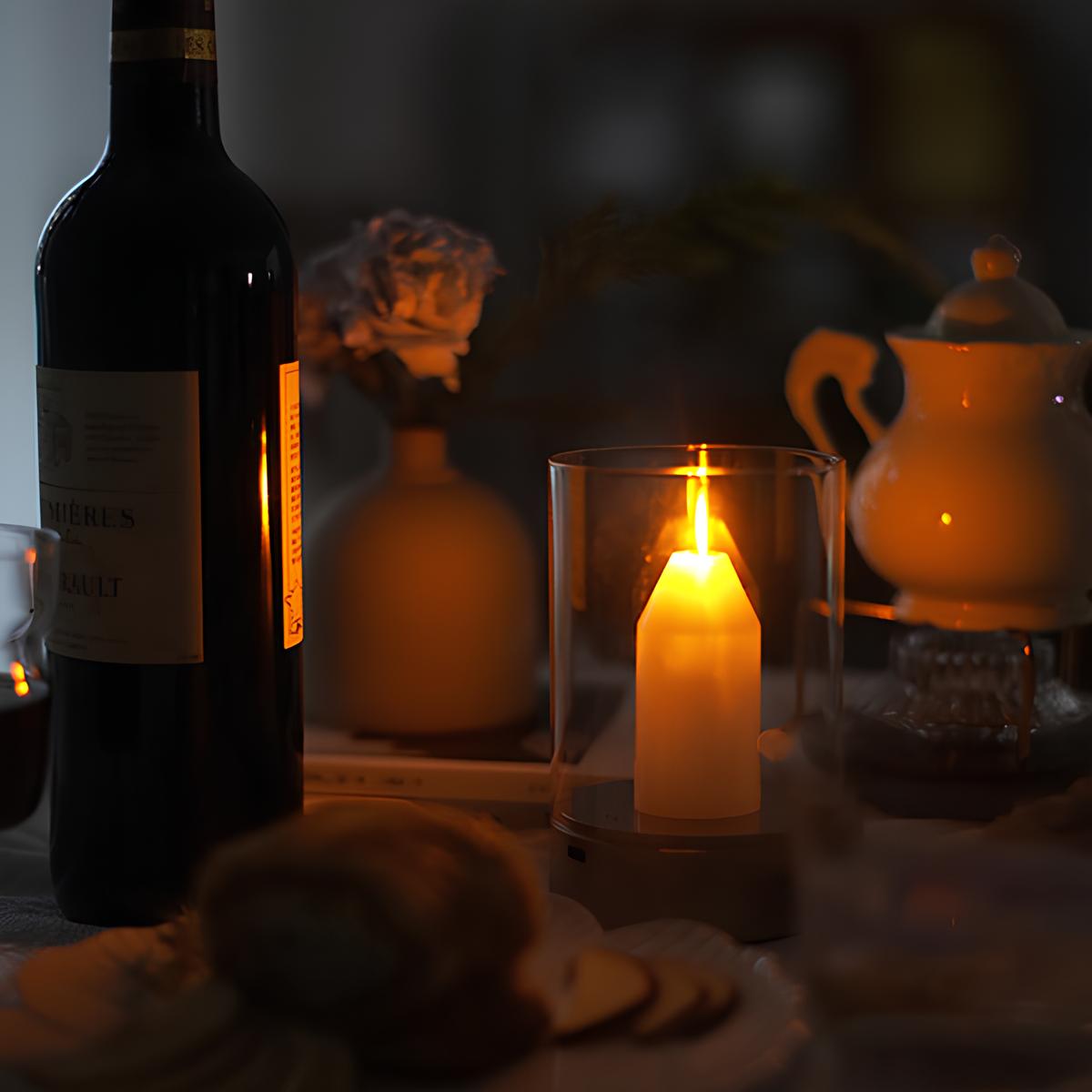 Kerzenlicht-Dekoration mit Weinflasche, Teekanne und Blumen auf einem Tisch.