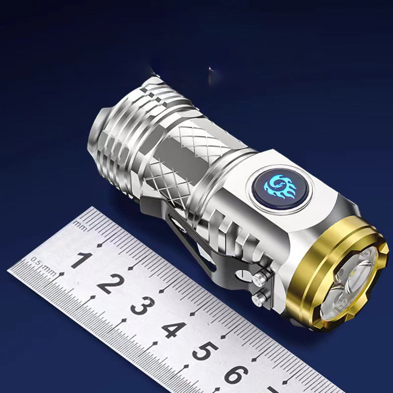 Silberne LED-Taschenlampe mit goldener Umrandung, kompakt, neben Lineal auf blauem Hintergrund.