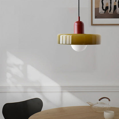 Moderne Hängelampe aus Glas in Rot und Gelb über einem Esstisch, minimalistisches Design.