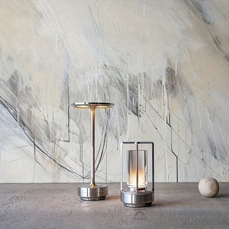 Moderne Tischlampen aus Metall, minimalistisch, silberfarben, auf Betonoberfläche vor abstrakter Wand.