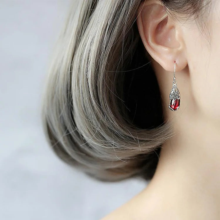 Frau mit silbernem Ohrring, roter Edelstein, elegantes Schmuckdesign, Nahaufnahme.