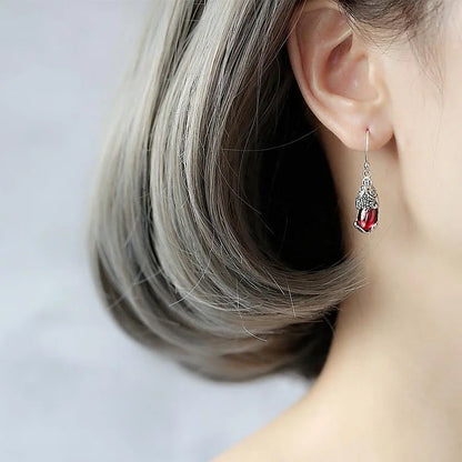 Frau mit silbernem Ohrring, roter Edelstein, elegantes Schmuckdesign, Nahaufnahme.
