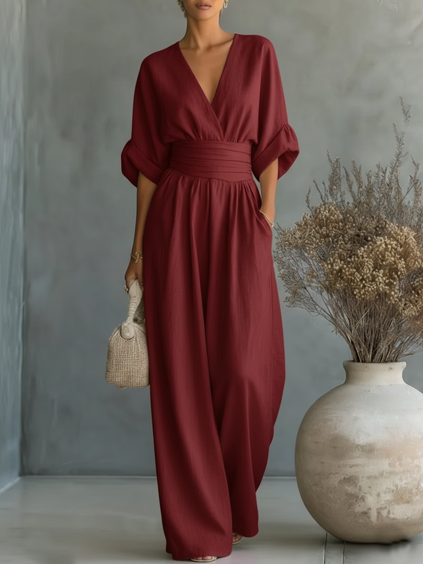 Kvinna i vinröd jumpsuit med wrap-ringning och bred midjedel, med handen i fickan 9