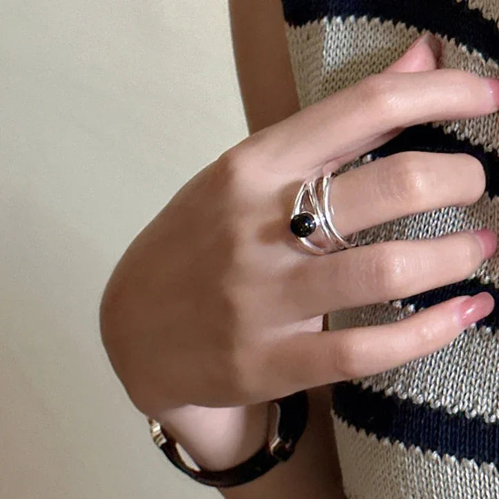 Silberner Ring mit schwarzem Stein, getragen an der Hand, modisches Accessoire, elegantes Design.