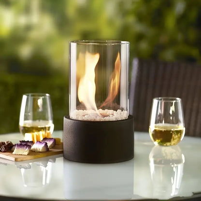 Glas-Feuerstelle mit Flamme, Tischdeko, modern, Outdoor, neben zwei Weingläsern auf Glastisch.